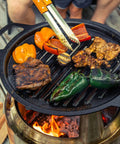 Outdoor grilling with cast iron pan, showcasing vibrant vegetables and meats, cooked on fire. Use Cast Iron Scrubber With Stainless Chainmail And Silicone Center, Food Safe And Rust Resistant, 304 Stainless Cleaner For Pan Grill Griddle Wok This Heavy Duty Scrubbing Tool That Removes Built Up Burnt On Gunk after cooking.