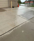 Cracked concrete driveway showing water pooling, demonstrating need for Tough As Nails Penetrating Concrete Sealer for protection.