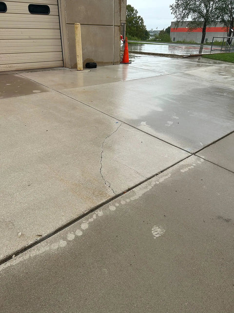 Cracked concrete driveway showing water pooling, demonstrating need for Tough As Nails Penetrating Concrete Sealer for protection.