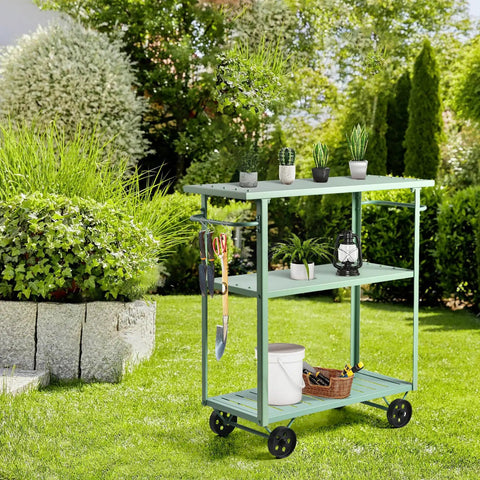 Flat Out Sturdy Three Tier Rolling Kitchen Cart Slick Green Metal Server With Tough Casters And Dual Hand Grips For Premium Indoor Coffee Tea Bar Display in garden with plants and tools.
