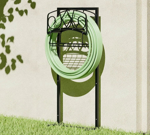Freestanding Garden Hose Organizer with Black Powder Coat Finish holding green hose, mounted against wall in garden.