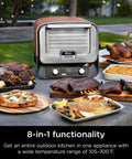 Woodfire Outdoor Pizza Oven 8 In 1 Portable Electric Roaster Heats Up To 700 Degrees Fahrenheit shown with cooked dishes outdoors.