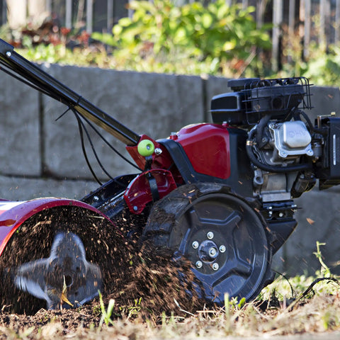 Pioneer Dual Direction Rear Tine Tiller With Counter Rotating And Standard Rotating Tines For Sod Busting And Seed Bed Prep Powered By A Light Quiet 99cc Viper Engine And Red Black Finish in use on soil, close-up view.