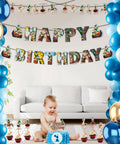 Baby's first birthday party with blue and gold balloons, cartoon character banners, and a cake in a living room setting.