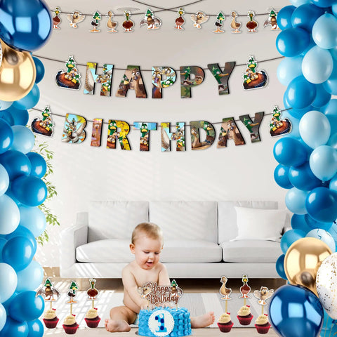 Baby's first birthday party with blue and gold balloons, cartoon character banners, and a cake in a living room setting.