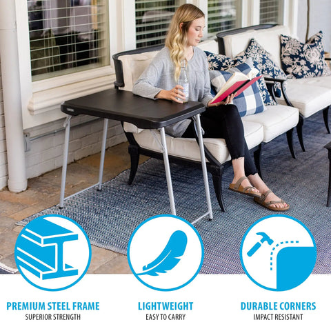 Woman using Stacking Compact Folding Table 30 By 20 Inches For Indoor And Outdoor Use Portable Black And Silver Folding Table on patio.