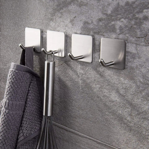 Self Adhesive Towel Hooks Four Pack Stick On Wall Stainless Steel 304 No Drill Bathroom Kitchen Hooks For Keys Robes And Towels Holds Up To 21 Pounds Heavy Duty Adhesive attached to a wall holding a towel and whisk