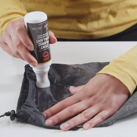Person applying Seam Grip TF Tent Fabric Sealer For Waterproofing And Restoring PU Coatings On Nylon Tent Floors, Rainflies, And Tarps