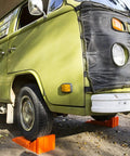 Stop N Chock 2 Pack For No Fuss Safe Parking And Easy Stabilization Interlocks With Levelers Durable Porous PLA Construction Delivers Strong Grip And Quick Setup in use with green RV on gravel