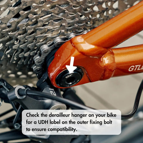 Close-up of UDH label on bike's derailleur hanger for compatibility check, featuring Universal Derailleur Hanger for SRAM UDH Standard Beefed Up 6061 Alloy Body With Fiber Reinforced Thermoplastic Black Finish Higher Stiffness Strength And Toughness For Long Lasting Shifting And Reliability