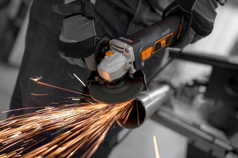 WEN 7-Amp angle grinder with 4-1/2-in wheel, orange/black body, grinding metal (close-up)