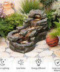 Epic 37 Inch Outdoor Floor Standing Five Tier Rock Waterfall Fountain With LED Lights for Patio, surrounded by plants and stones