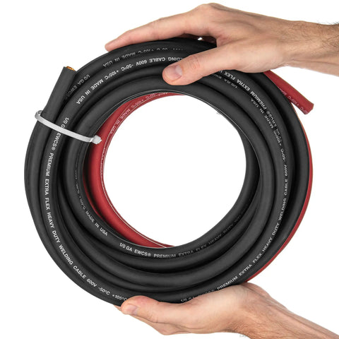 Hands holding coiled 1/0 Gauge Extra Flexible Welding Cable Set 10 Ft Black And Red Copper Pro Grade Industrial 600 Volt Welding Leads