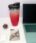 24 Oz cup with lid from 24 Oz Cups With Lids And 6 Fin Extractor Blade Replacement Kit For Nutri Ninja Auto IQ Blenders next to laptop