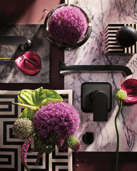 Genta LX Modern Wall Mount Pivoting Toilet Paper Holder in matte black on marble with flowers and decor