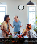 Three women socializing in a brightly lit kitchen using LED Light Bulb 60W Equivalent A19 Four Pack, 8.5W Efficient Daylight Frosted.