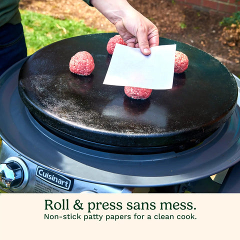 Hand placing patty paper on raw burger patties on grill from Smash Burger Kit With Cast Iron Press, Spatula, Seasoning Shaker And Patty Papers For Perfect Grillin At Barbecues And Tailgates, Mess Free Prep Every Time.
