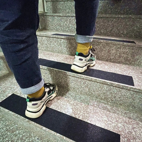 Person walking on stairs with Heavy Duty Anti Slip Tape 6 Inch By 35 Feet With 80 Grit Friction Grip For Indoor Outdoor Stairs Non Skid Traction.