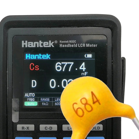 Digital LCR meter displaying a measurement next to a yellow capacitor labeled 684 from Ultimate Multilayer Ceramic Capacitor Value Kit.