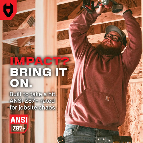 Man wearing ANSI Z87.1 clear safety glasses with side shields, using a power tool in a construction site, showcasing durability.