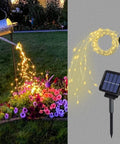 Solar Powered Fairy Lights Outdoor Waterproof 200 LEDs Copper Wire String Lights With 8 Modes Waterfall Style Firefly Vine Lights For Garden Trees Christmas Decor Dope Mom Gift illuminating a garden at night.