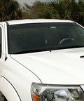 White pickup truck with black antenna, palm trees in background