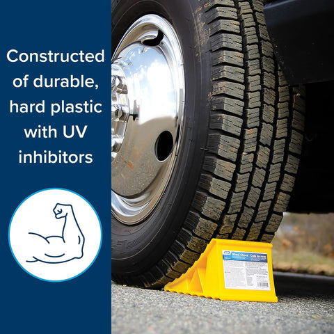 Camco RV wheel chock, yellow plastic, positioned under tire to prevent movement.