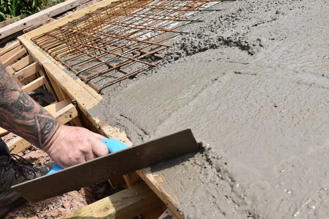 Worker using Pro-Grade Magnesium Concrete Float 3-1/8 x 16 In with beveled ends on wet concrete slab for smooth finish.