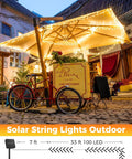 Solar Powered Outdoor String Lights 40 Ft 100 LED With 8 Lighting Modes IP65 Waterproof Warm White illuminating a cafe patio.