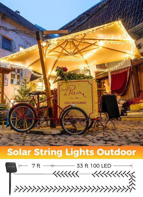 Solar Powered Outdoor String Lights 40 Ft 100 LED With 8 Lighting Modes IP65 Waterproof Warm White illuminating a cafe patio.