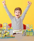 Magnetic Tile Idea Book With 300 Builds, 230 Page Illustrated Guide For Kids Ages 3 And Up, Includes Magnet Race Tracks And Marble Runs To Boost Creative Stem Play And Colorful Tile Creations. Child with magnetic tile construction layouts on table.