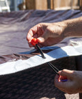 Hands securing Tough As Nails Waterproof Reversible Tarp 12 By 24 Feet Thick 14 Mil Industrial Grade Tarp With Double Reinforced Corners