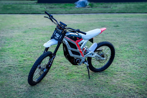 Adult Electric Dirt Bike Built To Shred With Raw Torque And 53 MPH Top Speed displayed on grass with knobby tires and sturdy chassis.