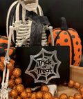 Skeleton decor holding Trick or Treat blank anodized aluminum engraving sheet with pumpkins and orange glitter balls