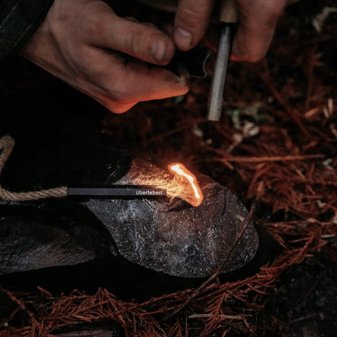 Person using All Weather Fire Starter Kit With Paraffin Wax Infused Hemp Wicks And Aluminum Bellow Sleeve 60 Minute Burn Waterproof Rope Match Camping Essentials For Quick Ignition In Rain Or Snow on rocky surface