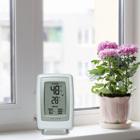 Indoor Outdoor Digital Thermometer With Wireless Temperature Sensor And Hygrometer For Home Use on windowsill next to plant