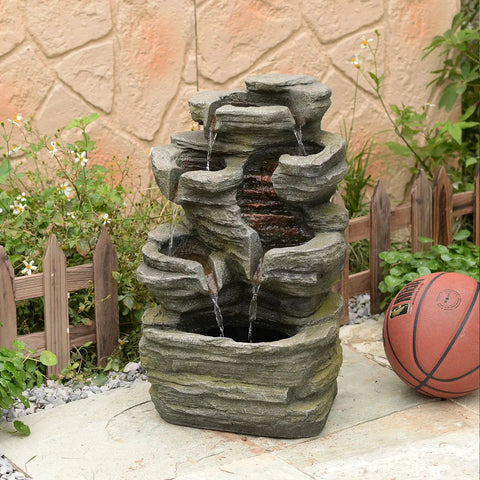 Six Tier Cascading Rock Outdoor Water Fountain With Lights For Garden Patio Backyard Deck And Porch No Fuss Setup With Pump 24.4 Inch High 110V Plug standing on a patio with a basketball beside it.