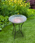 Handpainted Mosaic Flower Fusion Glass Pedestal Bird Bath For Outdoor Patio Garden Backyard Deck Decor, 21 Inch Height In Blue And Purple, Multi Functional Waterer Or Bird Feeder With Foldable Stand in a garden setting.