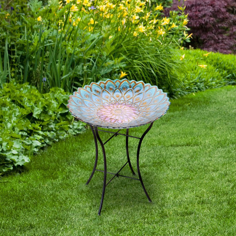 Handpainted Mosaic Flower Fusion Glass Pedestal Bird Bath For Outdoor Patio Garden Backyard Deck Decor, 21 Inch Height In Blue And Purple, Multi Functional Waterer Or Bird Feeder With Foldable Stand in a garden setting.