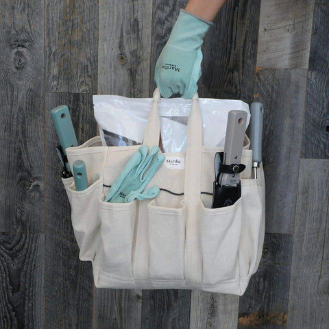 Heavy-Duty Canvas Garden Bag With 6-Inch Exterior Pockets And 11-Inch Interior Pockets held by a hand wearing gardening gloves