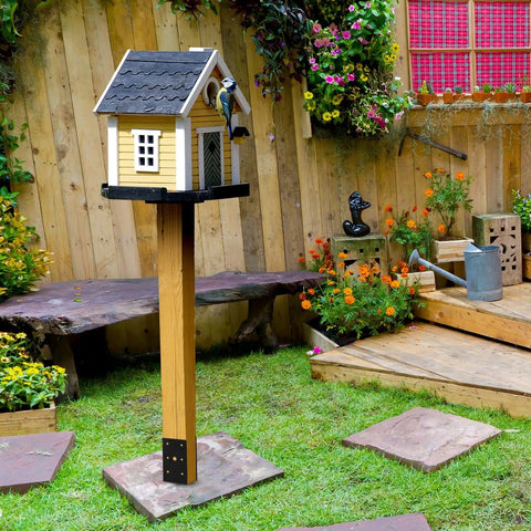 Backyard scene with a wooden post and birdhouse, secured on a Heavy Duty U Shaped Fence Post Anchor Ground Spike 4 x 4 In Concrete Base.
