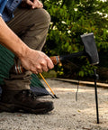 Top Shelf 14 Inch Wood Splitting Maul With Forged Steel Head And Kickless Grip being used to hammer a tent stake at a campsite.