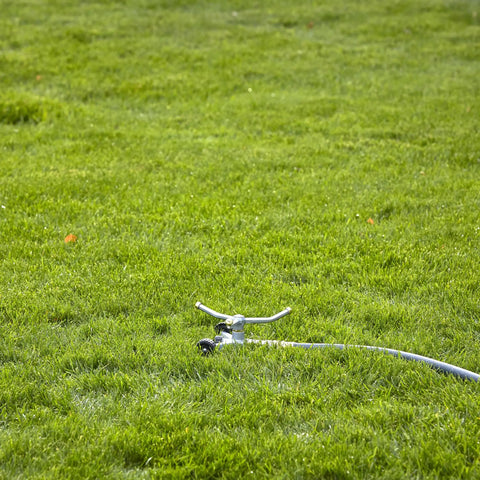 Heavy Duty Spinning Sprinkler With Wheeled Base For 360 Degree Coverage In Flower Beds And Vegetable Gardens on grassy lawn