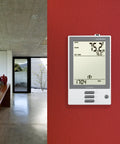 Programmable Thermostat With Floor Sensor And Class A GFCI, White Finish, NHance UDG-4999 Model, mounted on red wall in home.