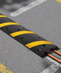 Beefy Rubber Driveway Speed Bumps 2-Pack, 6-Foot 2-Channel Modular Traffic Humps, 22,000 Lbs Axle Load Capacity, 72-Inch Cable Protector Ramp on asphalt with visible cables