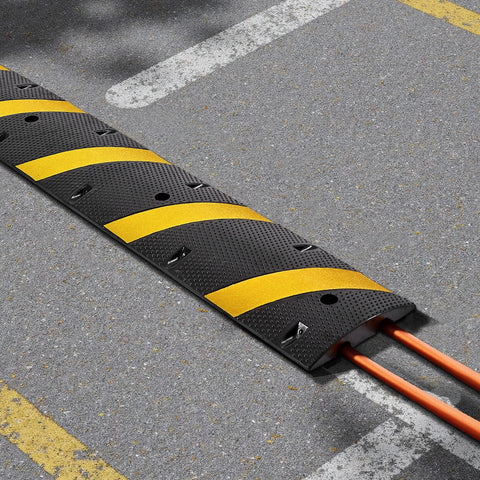 Beefy Rubber Driveway Speed Bumps 2-Pack, 6-Foot 2-Channel Modular Traffic Humps, 22,000 Lbs Axle Load Capacity, 72-Inch Cable Protector Ramp on asphalt with visible cables