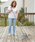 Heavy Duty Angle Broom Featuring Rigid Bristles And An Extended Handle That Smashes Through Stubborn Dirt And Leaves On Patios Garages And Commercial Floors Like Butter being used to clean leaves on a wooden deck.