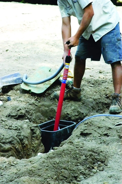 Person using Siphon King 24 Inch Hand Transfer Pump With 36 Inch Hose for water removal from trench job site in USA