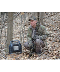 Hunter with Hunting Buddy Space Heater 6K To 12K BTU Outdoor Heater in camouflage finish amidst trees for up to 300 sq ft