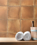 Rustic Cotto 13x13 Porcelain Tile For Floor And Wall, Glazed Textured Finish, shown as wall backdrop with rolled towels and bucket.